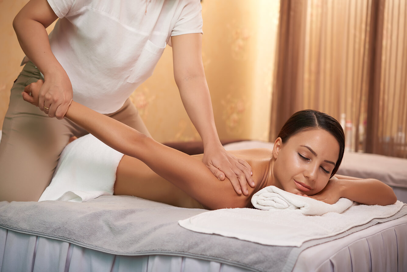 Therapist stretching client's arm during an Asian massage therapy session