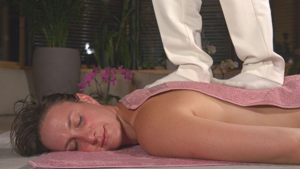Therapist applying foot pressure to client’s back during Ashiatsu massage